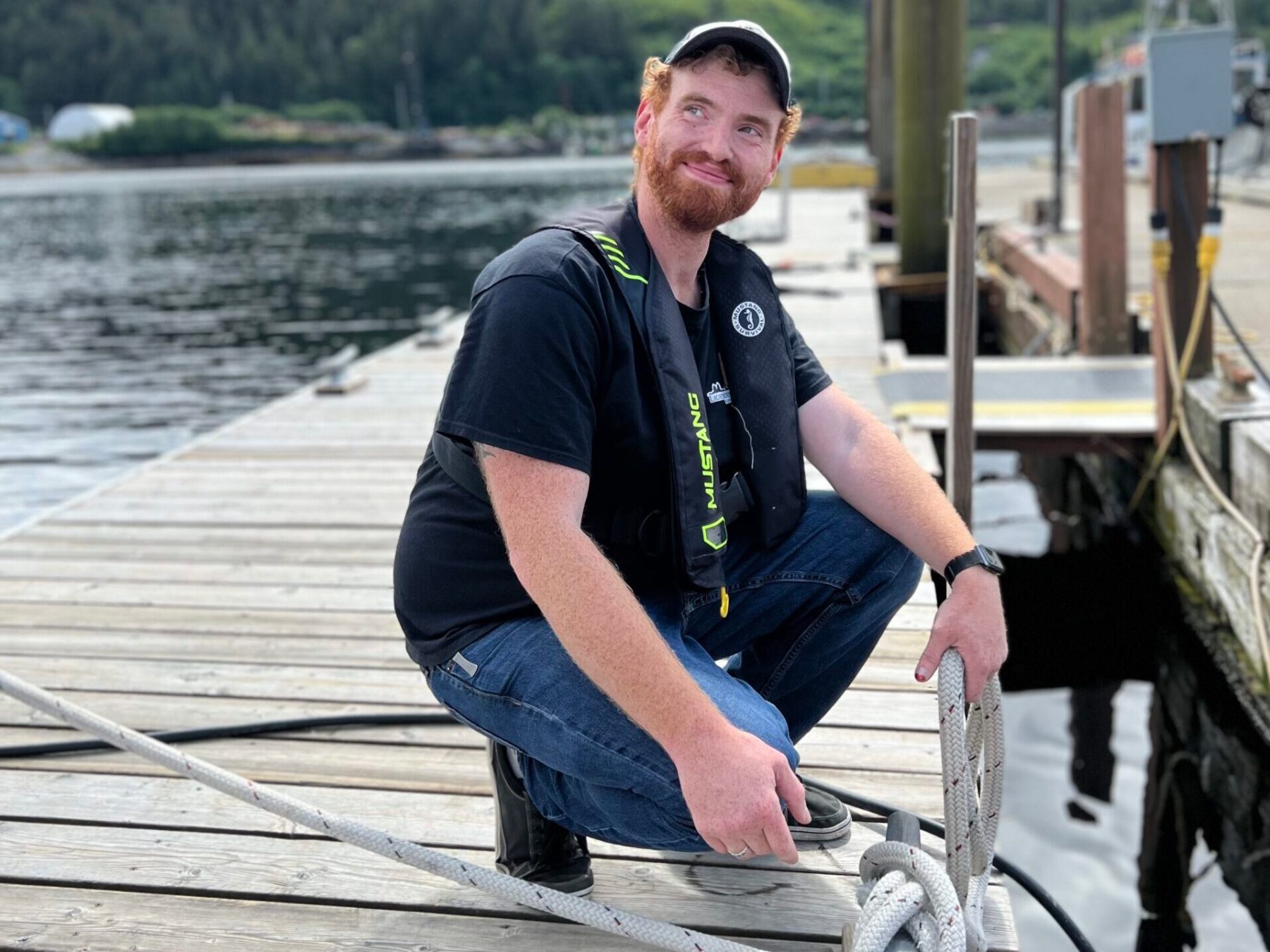 a man sitting on a dock next to a body of water