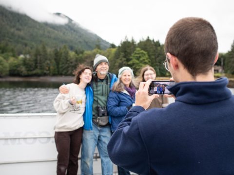 a group of people getting their photo taken in front of Totem Bight State Park
